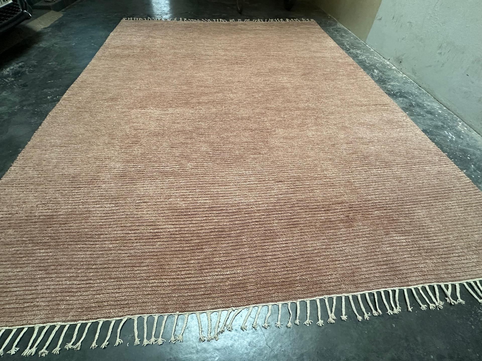 Handknotted ribbed wool rug in rust terracotta with textured linear pattern and fringe